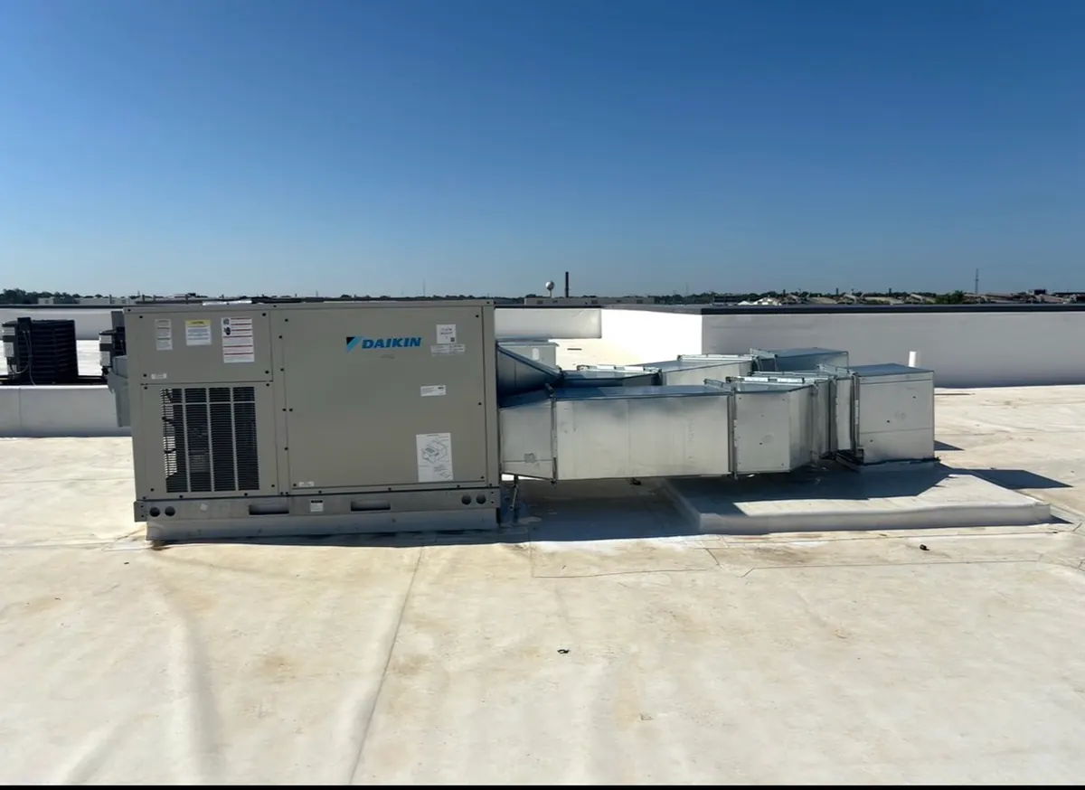 Packaged rooftop unit with a sheet-metal supply trunk and takeoff boxes on a membrane roof
